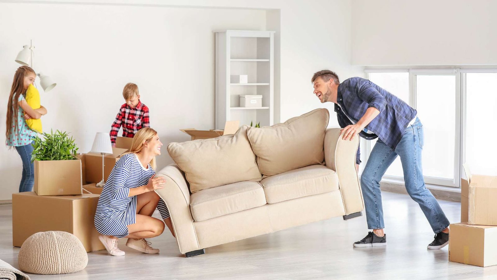 a man and a woman moving a sofa with their children